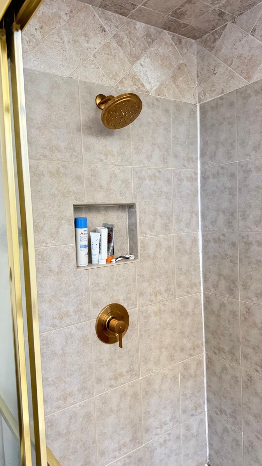 Ducha con azulejos, regadera y válvula dorado cepillado